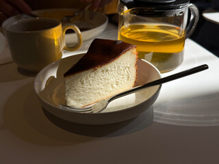 Basque cheesecake and green tea on table. Cafe breakfast concept. Handmade smartphone photo, selective focus, harsh sunlight, non AI