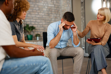 Supportive colleagues comforting stressed male coworker in office