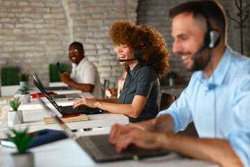 Laughing woman working in a busy modern call center