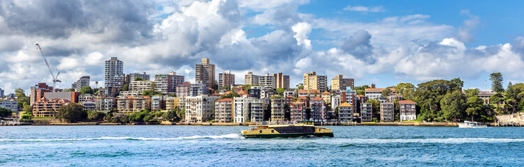 Panorama of the prime residential real estate of the Sydney Harbour Lower North Shore, with ferry boat, on a summer afternoon. The suburban districts of Kirribilli and Beulah Street Wharf
