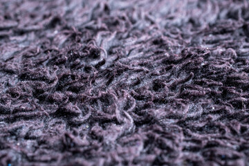 Extreme close up of deep purple synthetic rug fibers. Detailed soft hairy texture and messy pile pattern for interior decor background concept.  © Ryan