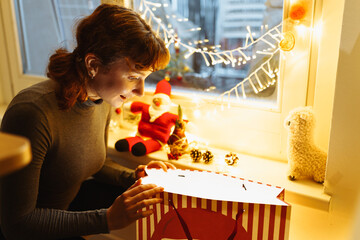 Young girl with gift box near christmas tree at home