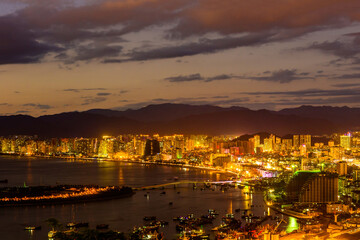 Fototapeta premium Sunset view of Sanya town with city lights. View from Luhuitou Park on Hainan Island of China.