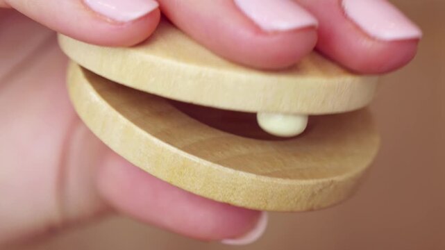 Woman holding in hands and playing wooden Castanets musical instrument close up