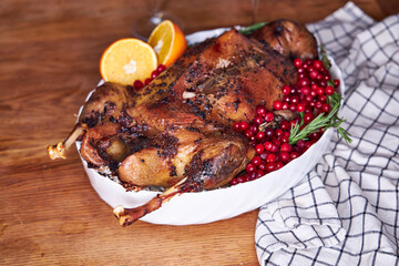 Top view of festive roasted goose served with cranberries, oranges and buckwheat on a wooden table....