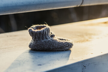 Mały, ręcznie robiony bucik dziecięcy leżący na ławce w ciepłym, wieczornym świetle © Henryk Niestrój