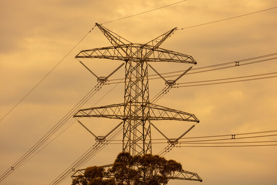 Photograph of a large electricity Transmission Tower set against a vibrant orange sunset sky in the town of Kemps Creek in New South Wales, Australia.
