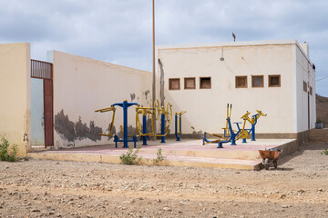 Outdoor old fitness area with kettlebells, tires, and gym equipment under cloudy sky in urban...
