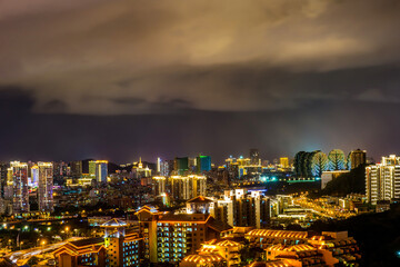 Fototapeta premium Night cityscape with clouds illuminated with city lights. Sanya town, Hainan Island of China.