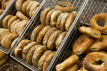 Assortment of bagels in a metal bin at a bagel shop.