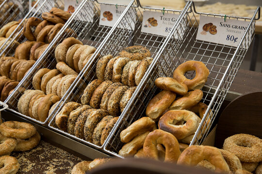 Assortment of bagels in a metal bin at a bagel shop.