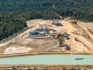 Drone aerial photograph of a large operational industrial sand quarry located within a vibrant and evergreen forest in the Blue Mountains in New South Wales, Australia.