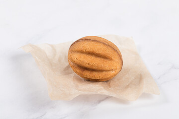 Cookie in the shape of nut. Stuffed with boiled condensed milk. On paper. White background. Close up