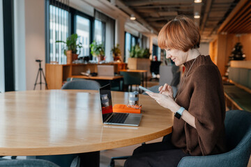Middle-aged female working quietly on laptop in warm interior