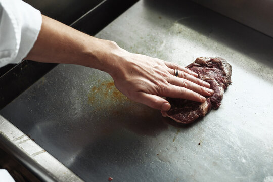Chef expertly presses meat on hot griddle to create savory crispy crust