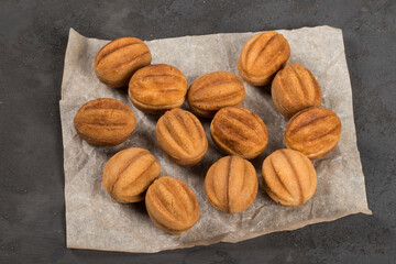 Cute cookies in the shape of nuts. Stuffed with boiled condensed milk. On paper. Dark gray background