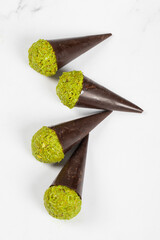 Dubai chocolate dessert. Dark chocolate cone with a ball of crispy kataifi dough with pistachio paste. White background. Top view	
