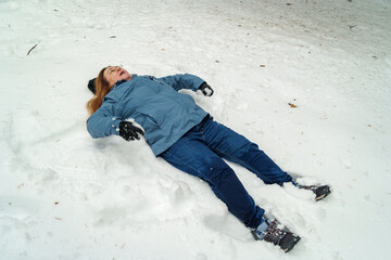 Adult woman lying on snow after slipping in winter outdoors