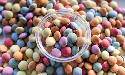 Colorful chocolate candy pieces spilling from bowl