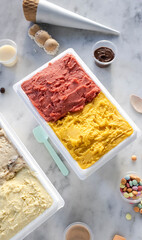 Gelato tubs with various toppings on marble