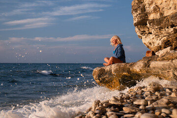 Child, Coast, Sea - Young boy sits on cliff overlooking the ocean with waves crashing on the rocks.