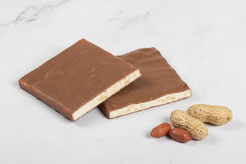 Nougat with nuts in milk chocolate. White background. Close-up