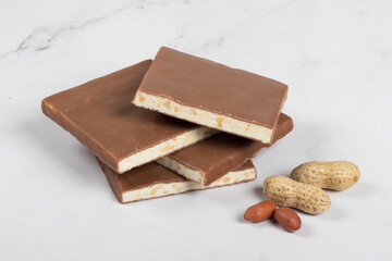 Nougat with nuts in milk chocolate. Square shape. White background. Close-up