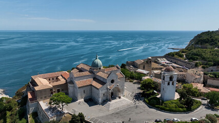 Aerial drone panorama of seaside rooftops in Italy with calm blue sea stretching to the horizon.