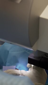 Lasik treatment. Laser vision correction. Doctor examines fundus in microscope, patient under sterile cover.