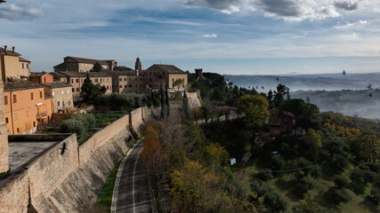 Fototapeta premium Aerial drone view of a hilltop village in Italy overlooking surrounding countryside. Historic architecture and scenic landscape.