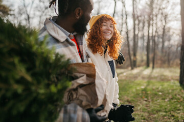 Young couple is packing Christmas tree on the car