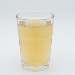 Studio shot of pale apple juice in a clear glass, perfectly centered on a seamless white backdrop