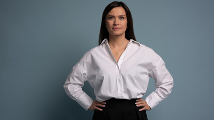 Beautiful, attractive, middle aged woman wearing casual white shirt with arms crossed standing isolated on blue background
