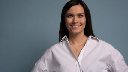 Beautiful, attractive, middle aged woman wearing casual white shirt with arms crossed standing isolated on blue background