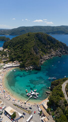 Fototapeta premium Vertical aerial view of crowded beach and turquoise bay in Paleokastritsa, Corfu, Greece