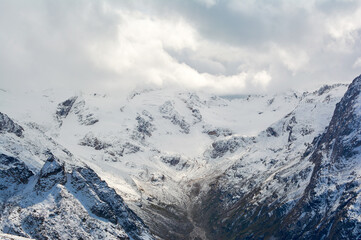 Snow-covered mountains stand as majestic white giants against sky, embodying winter's powerful alpine beauty.
