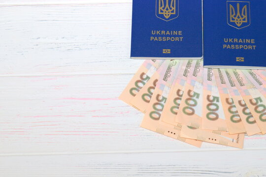 Ukrainian foreign biometric passport with inscription in Ukrainian - Ukraine passport with hryvnia notes on white wooden background. The concept of money, holidays, travel