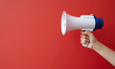 person hand grasps white megaphone vibrant red background expansive open space front speaker illuminated
