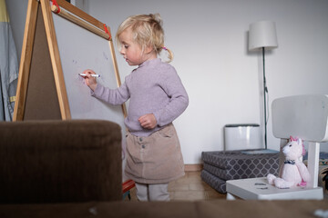 Cute four year old blonde girl playing teacher and teaching numbers to her stuffed toy.