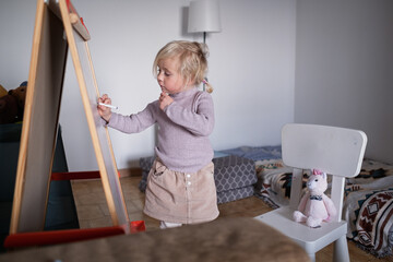 Cute four year old blonde girl playing teacher and teaching numbers to her stuffed toy.