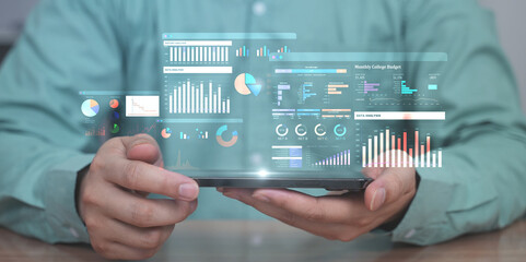 Hands holding tablet with futuristic business data dashboard, featuring charts, graphs, statistics and performance analytics overlay.
