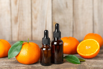 Tangerine essential oil on a wooden table. Bottles of citrus essential oil and sliced ​​fruits. Fragrant tangerine oil with tangerines. Cosmetic oil for spa treatments. Aromatherapy concept. 