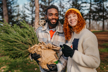 Fototapeta premium Boyfriend and girlfriend having fun time together while carrying their new Christmas tree home