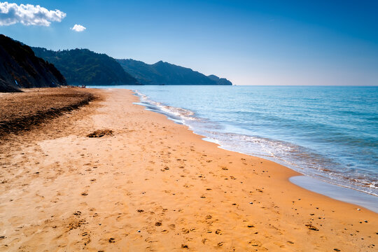 Wide golden-sand Arillas Beach on coast Corfu. Greek coastal holiday landscape with crystal-clear waters in the Ionian Sea.