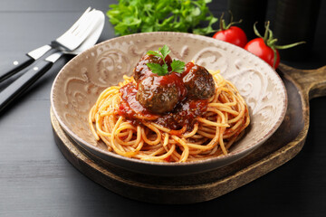 Fototapeta premium Delicious pasta with meatballs served on black wooden table, closeup