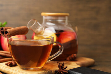 Aromatic fruit tea in glass cup, teapot, apple and spices on table, closeup. Space for text