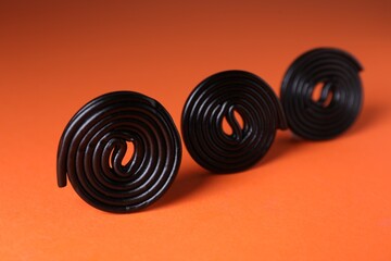 Natural licorice candies on orange background, closeup