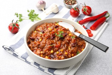 Delicious chili con carne served on light gray table, closeup
