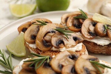 Tasty bruschettas with cream cheese, mushrooms, lime and rosemary on table, closeup