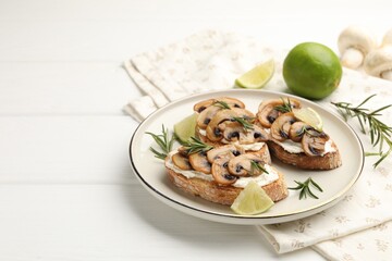 Tasty bruschettas with cream cheese, mushrooms, lime and rosemary on white wooden table, closeup. Space for text